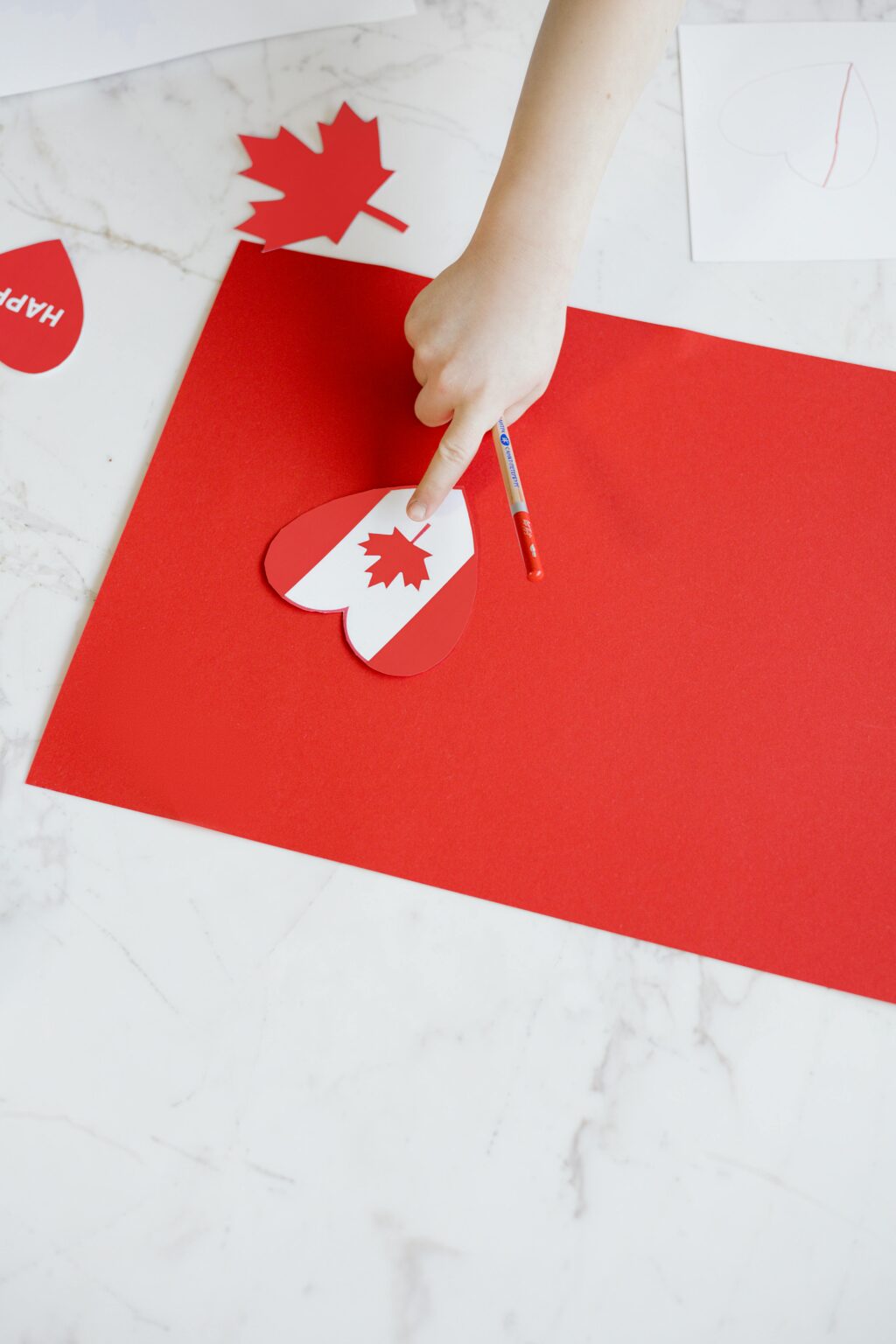 A child creating Canada-themed crafts with red paper cutouts, celebrating Canada Day.